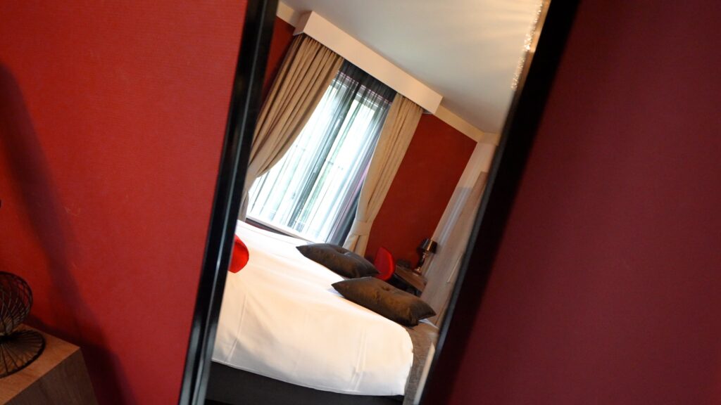 Hotelkamer weerspiegeld in een grote spiegel in Hotel De Wolfsberg