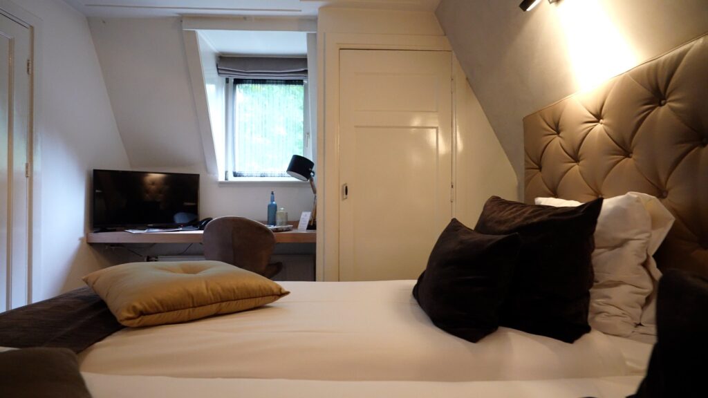 Hotelkamer onder de kap met werkplek en televisie in Hotel De Wolfsberg