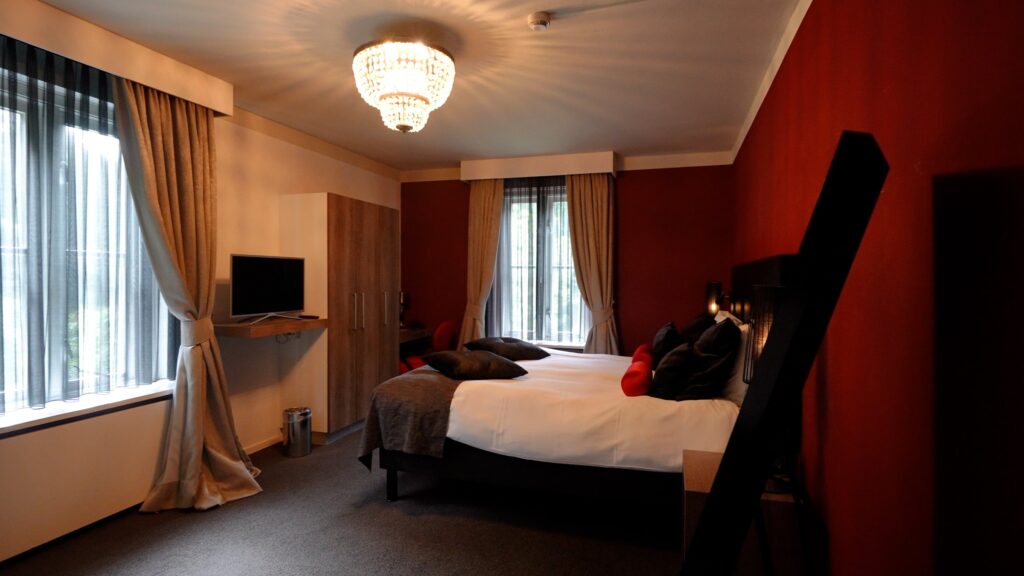 Ruime hotelkamer met warme wandkleur en zithoek in Hotel De Wolfsberg