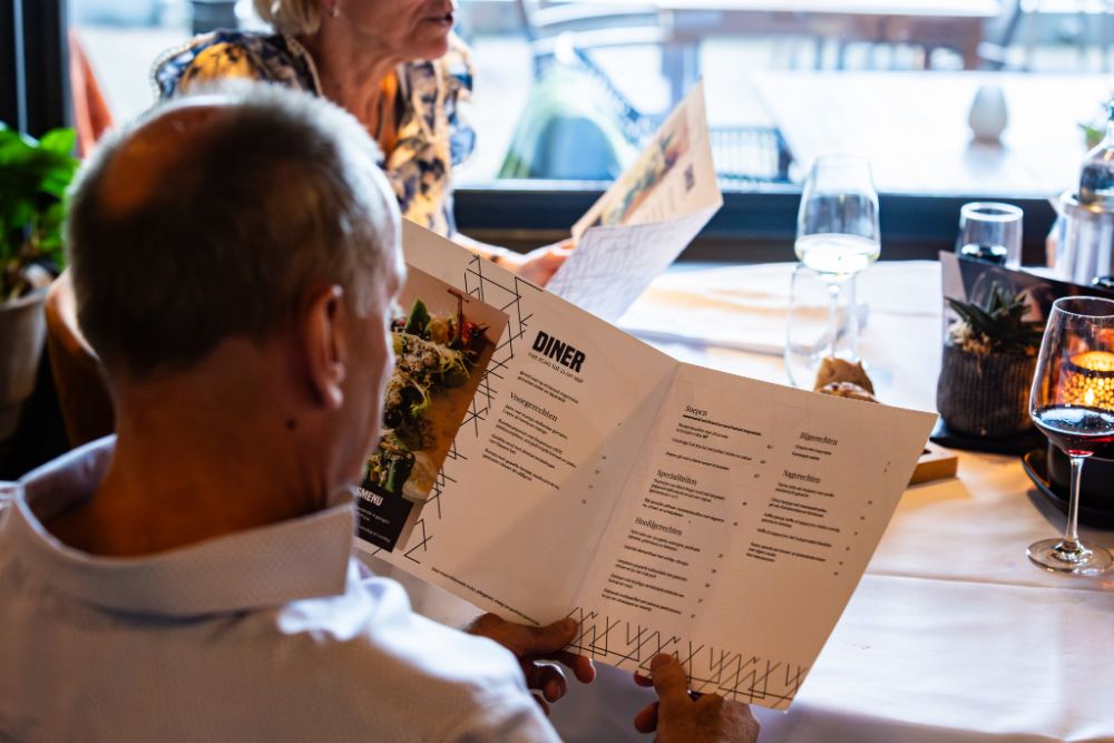 Een gast leest de menukaart aan tafel