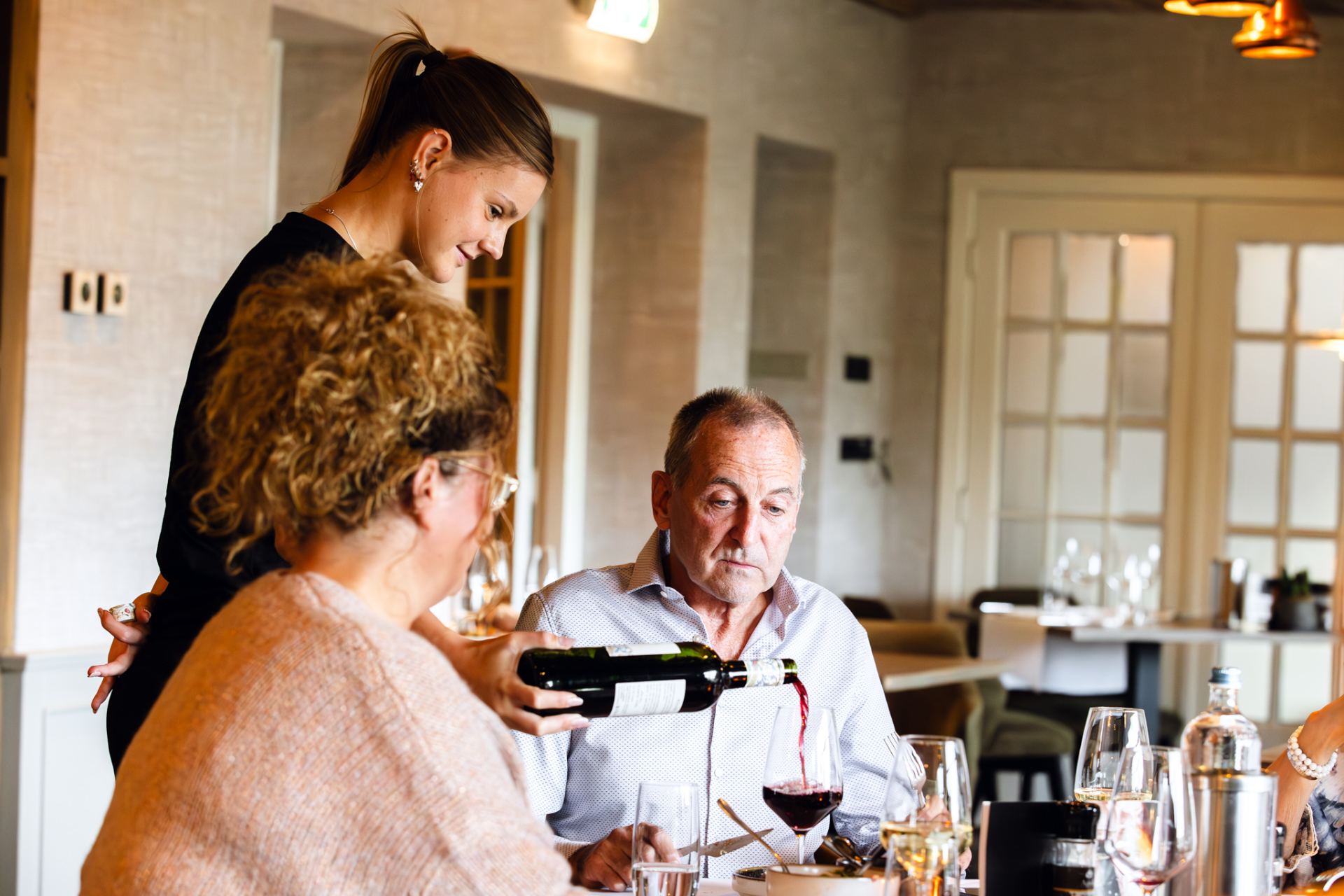 Een gast krijgt rode wijn ingeschonken aan tafel in het restaurant van De Wolfsberg