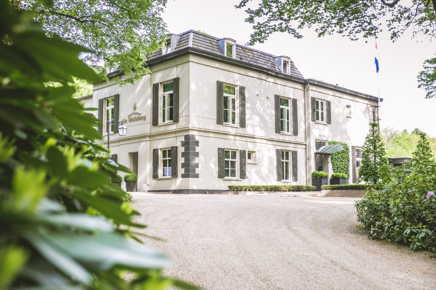 De witte villa van Hotel Restaurant De Wolfsberg tussen de bomen