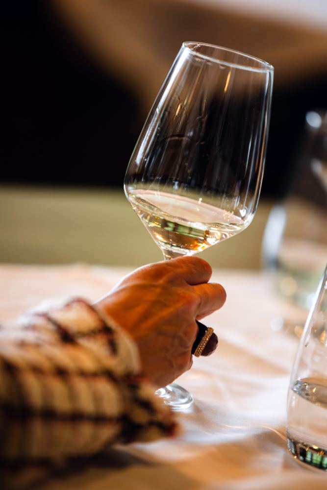 Een glas witte wijn wordt geheven aan tafel